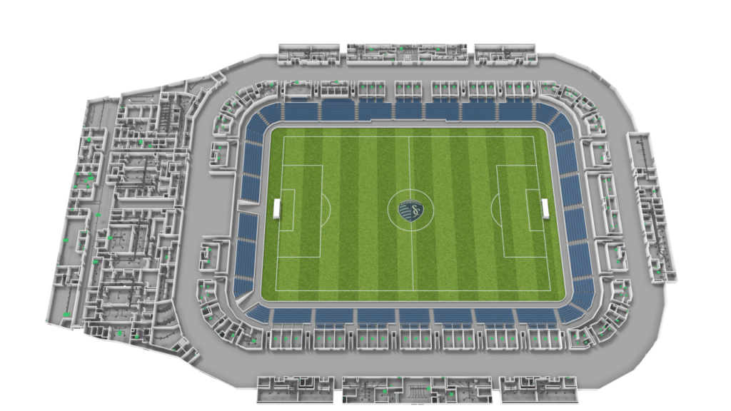 A top-down view of a soccer stadium with green grass, white field markings, blue stands, and detailed surrounding structures. The center of the field features a circular emblem.