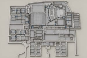 Architectural floor plan of a building layout, featuring a central gymnasium, an auditorium, and various classrooms connected by piping systems.